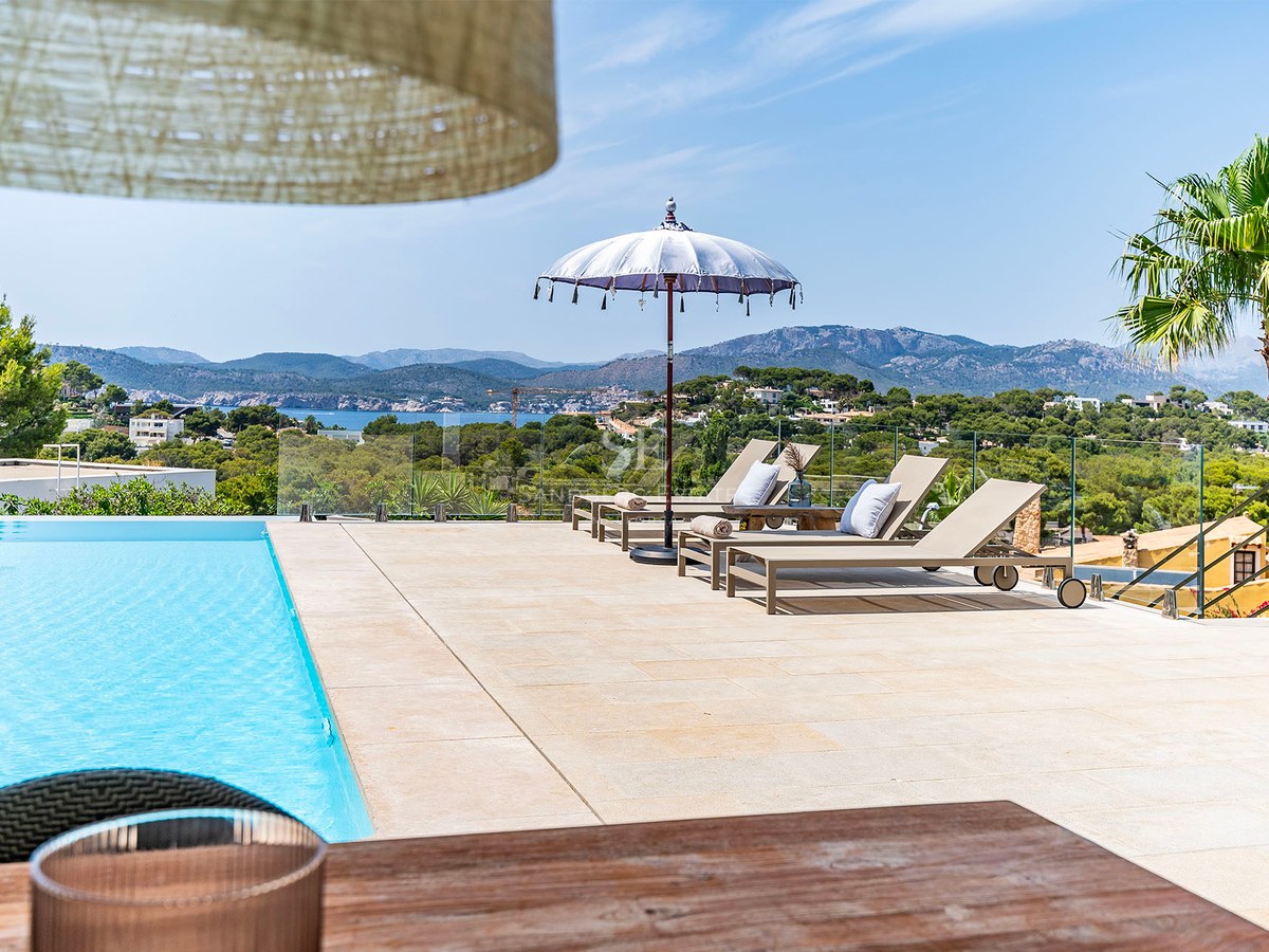 Vy över en lyxig modern villa med infinitypool, rymliga terrasser och panoramautsikt över havet. Minimalistisk och elegant design.