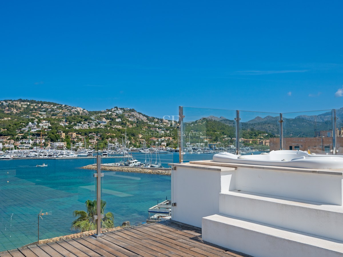 Rooftop terrace featuring a white jacuzzi, glass railings, and panoramic views of a marina and mountains.