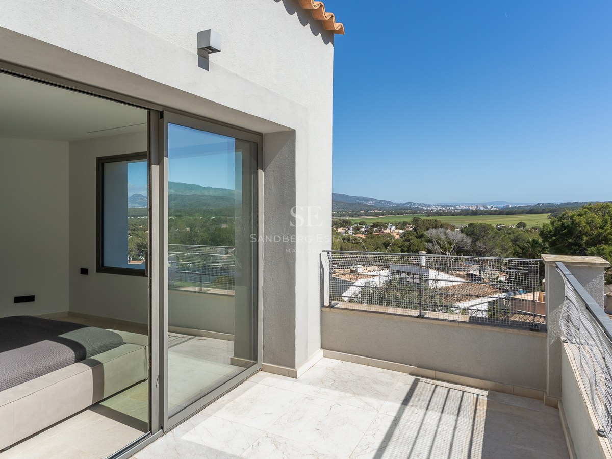 Private Terrasse mit Natursteinboden und Glasschiebetüren mit Blick auf ein grünes Tal.