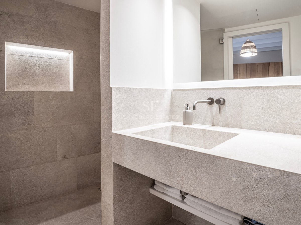 Modern bathroom featuring an integrated stone vanity, backlit mirror, and a walk-in shower with a lighted recessed niche.