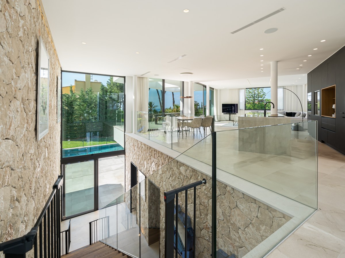 Vue en hauteur d'un salon et d'une salle à manger modernes à aire ouverte avec un mur en pierre naturelle et du verre.