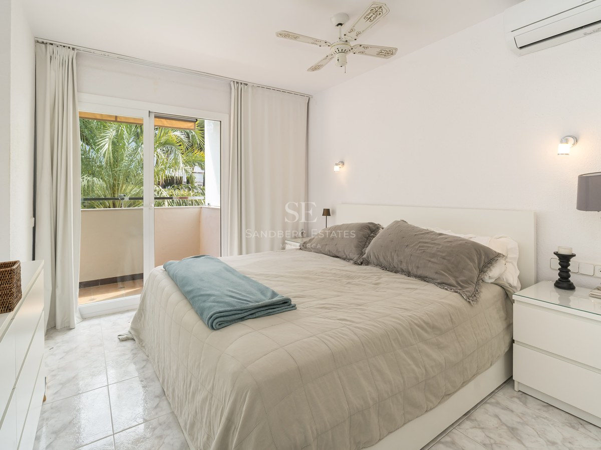 Chambre lumineuse avec lit double, sol en marbre et balcon offrant une vue sur des palmiers.