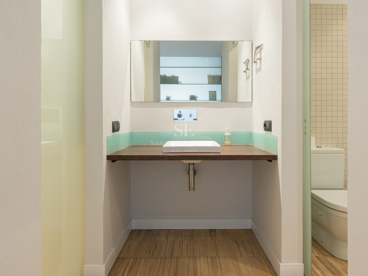 Bathroom featuring a floating wood countertop, white square vessel sink, rectangular mirror, and teal glass backsplash.