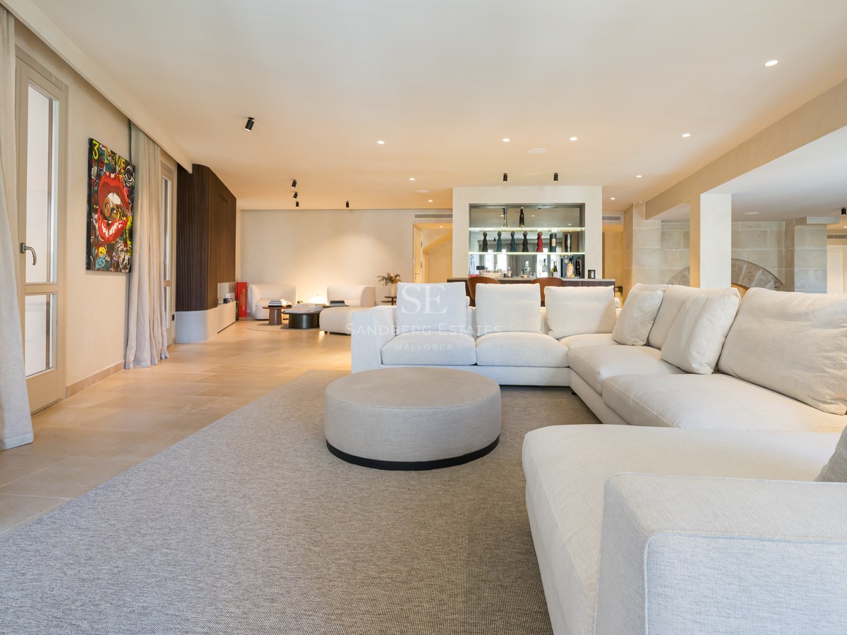 Large white sectional sofa in a spacious, modern living room with stone floors and a built-in bar area.