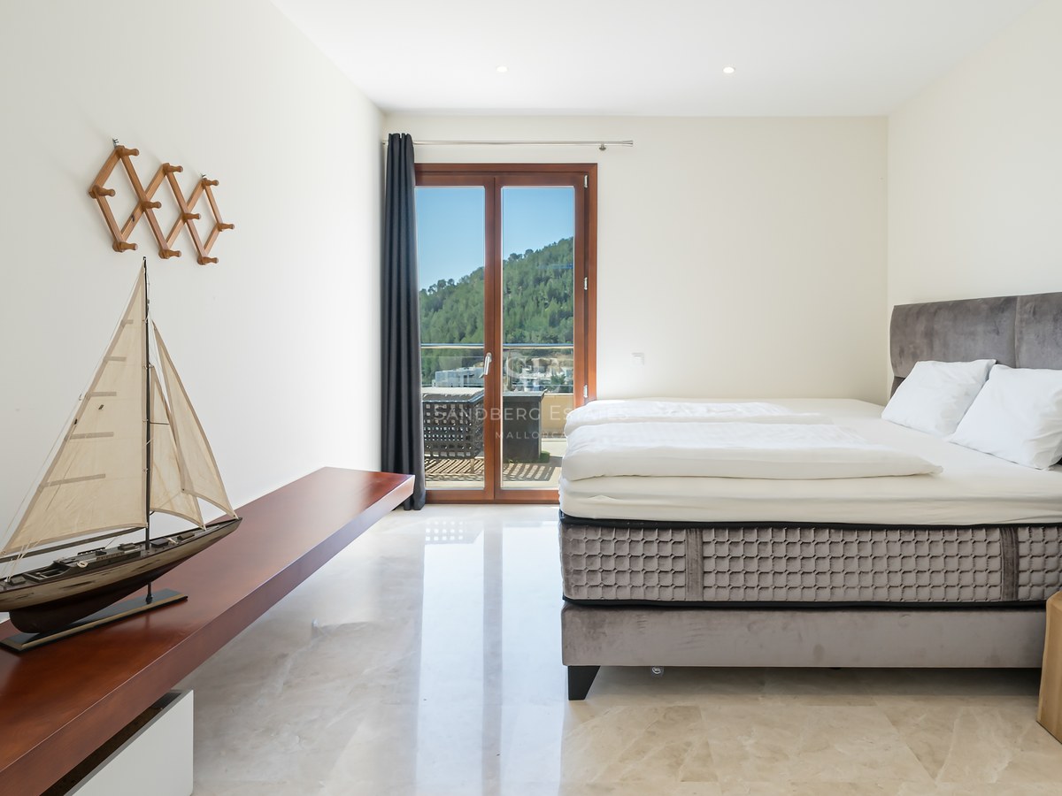 Dormitorio luminoso con suelos de mármol, cama de terciopelo gris y puerta de cristal con vistas a la montaña.