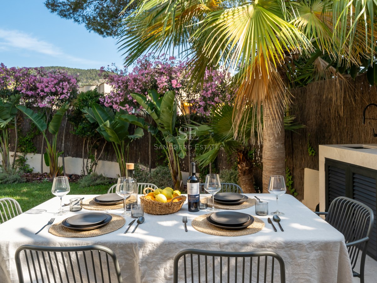 Table à manger extérieure pour six dans un jardin tropical à côté d'une cuisine d'été moderne en pierre.