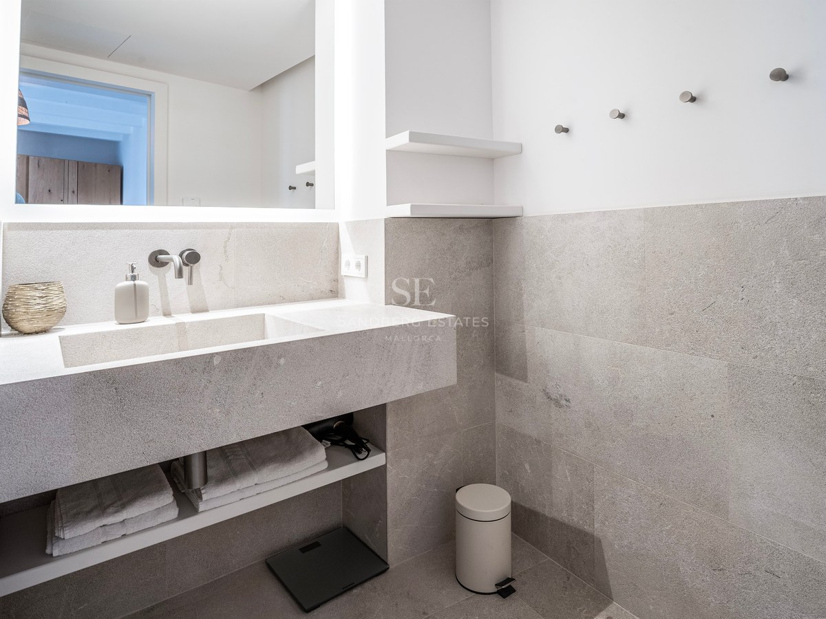 Modern bathroom featuring a grey stone floating vanity, integrated sink, and a large rectangular backlit mirror.