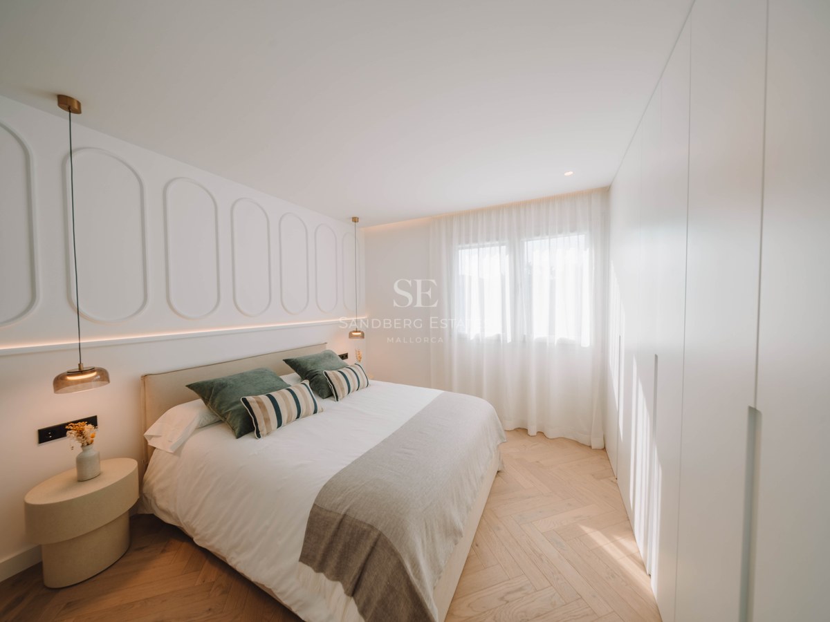 Chambre principale moderne avec lit double, moulures murales décoratives et parquet clair en point de Hongrie.