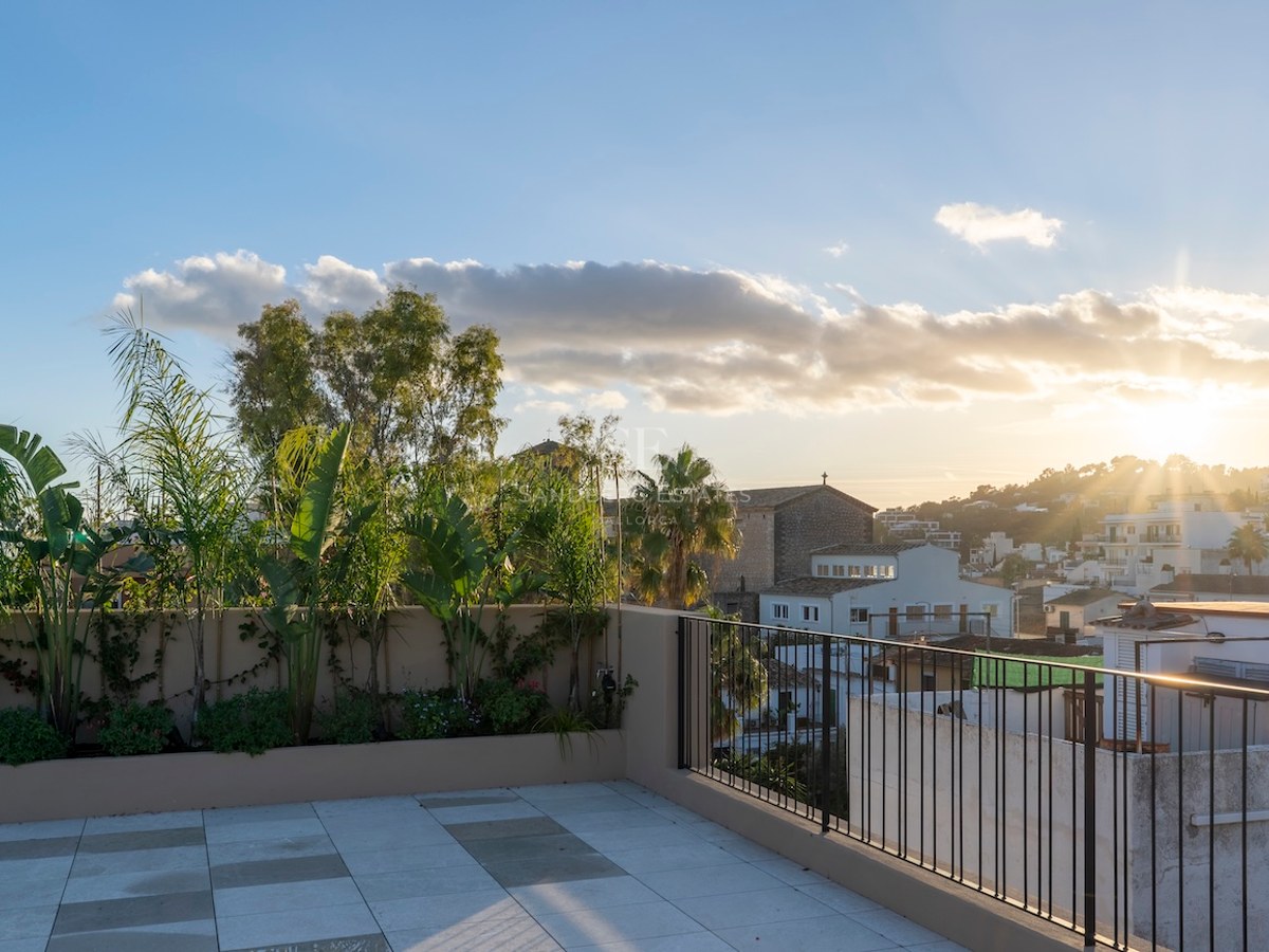 Terrasse de toit moderne avec carrelage en pierre et plantes tropicales, surplombant une ville méditerranéenne au coucher du soleil.