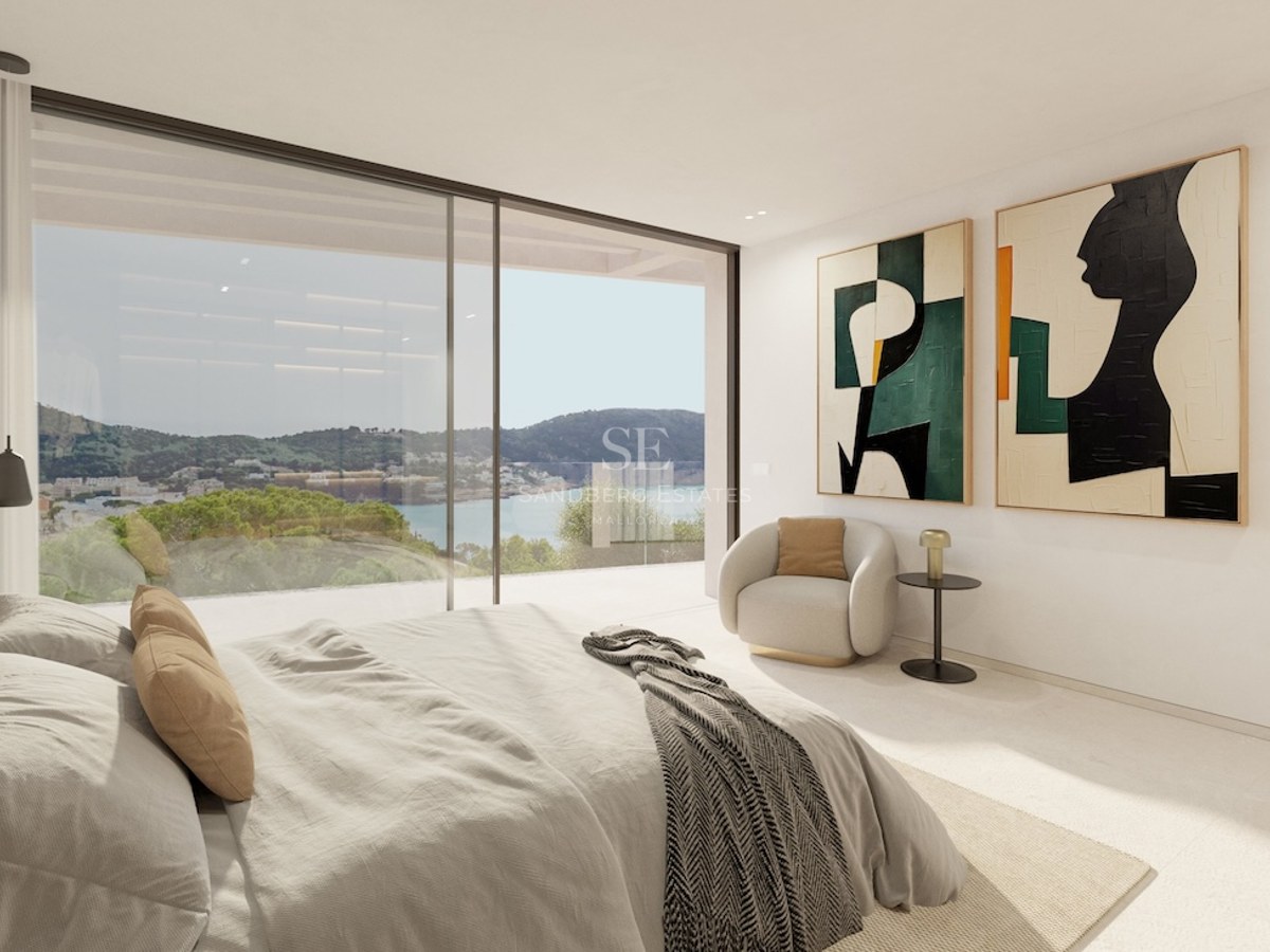 Chambre de maître moderne avec de grandes baies vitrées offrant une vue sur la côte et la mer.