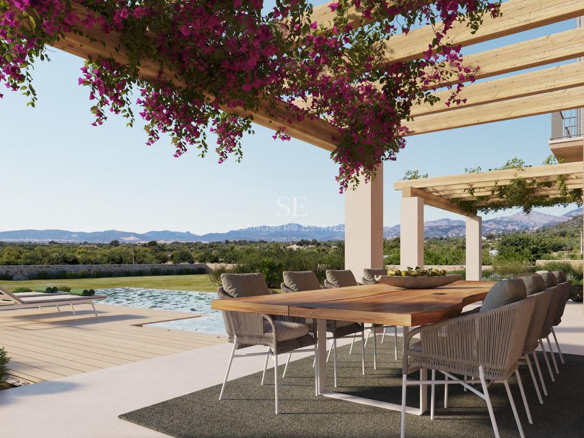 Table à manger en bois sous une pergola de bougainvilliers surplombant une piscine et des montagnes.