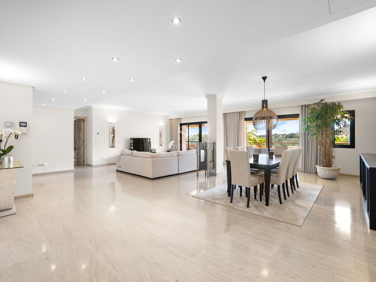 Intérieur lumineux à aire ouverte avec sols en marbre poli, un grand canapé blanc et une salle à manger moderne.