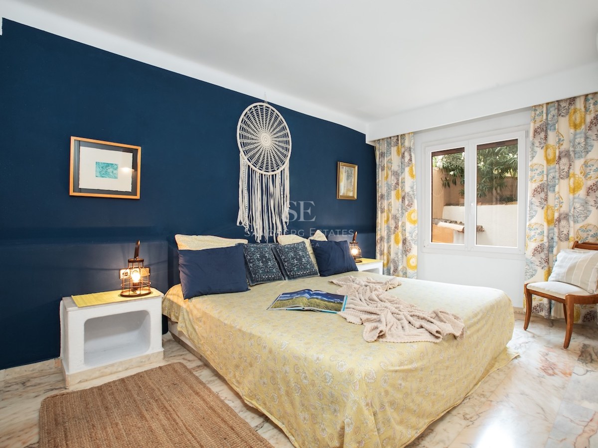 Chambre avec un grand lit, un mur d'accent bleu marine avec un attrape-rêve et un sol en marbre poli.