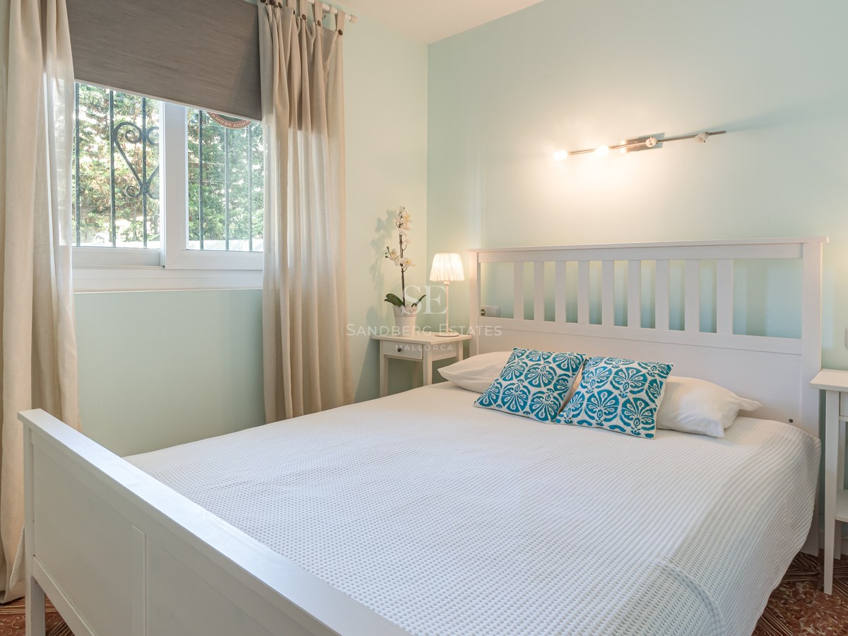 Chambre vert menthe avec lit en bois blanc, tables de chevet assorties et sol en carrelage traditionnel.