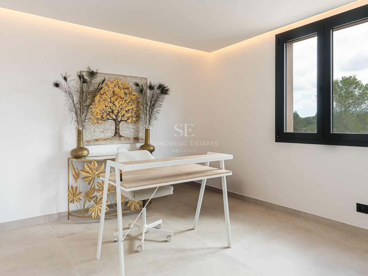 A modern study area featuring a white desk, gold artwork, and warm LED cove lighting in a white room.