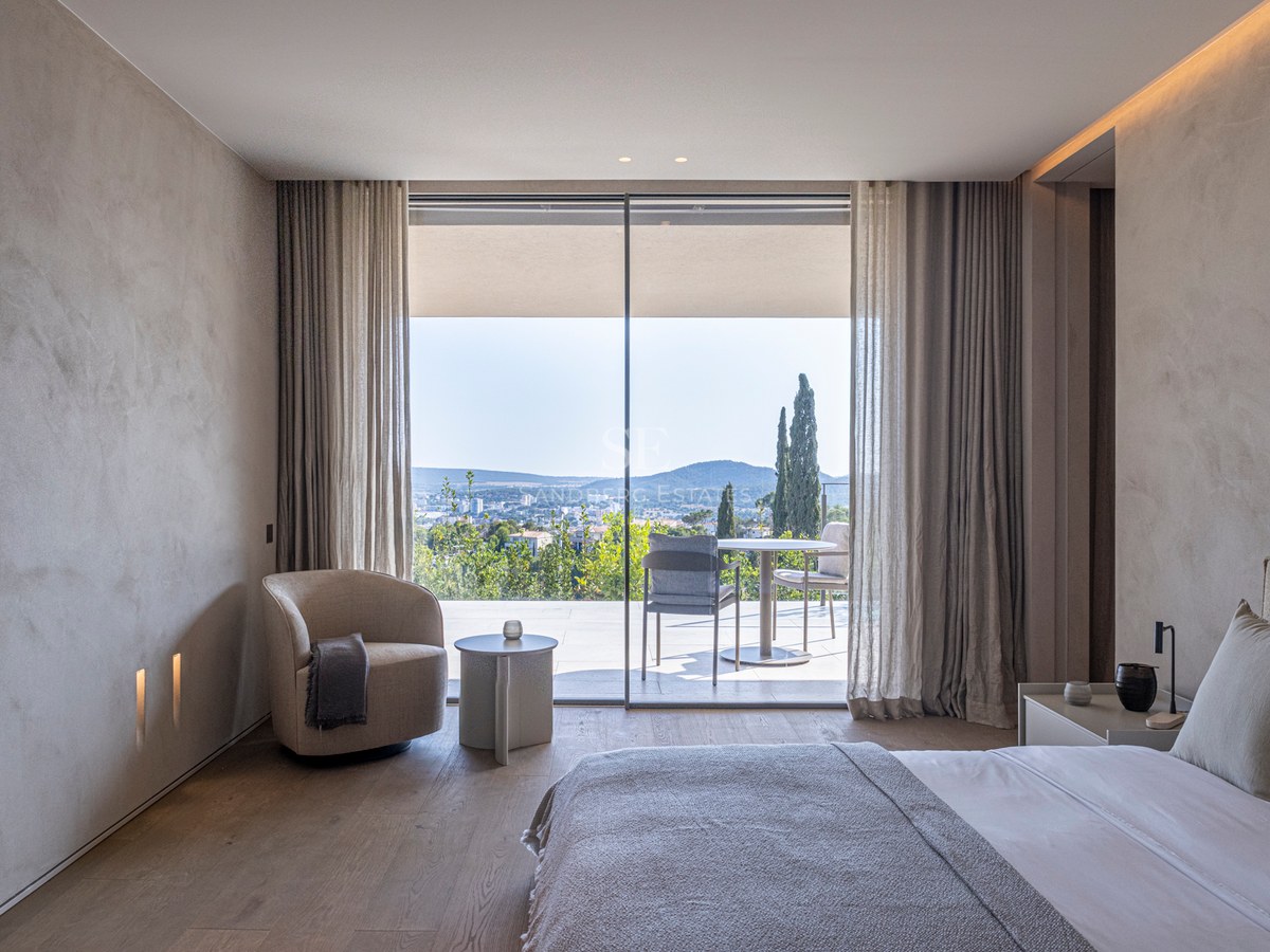 Chambre moderne avec parquet en chêne ouvrant sur une terrasse privée offrant une vue panoramique sur les collines.
