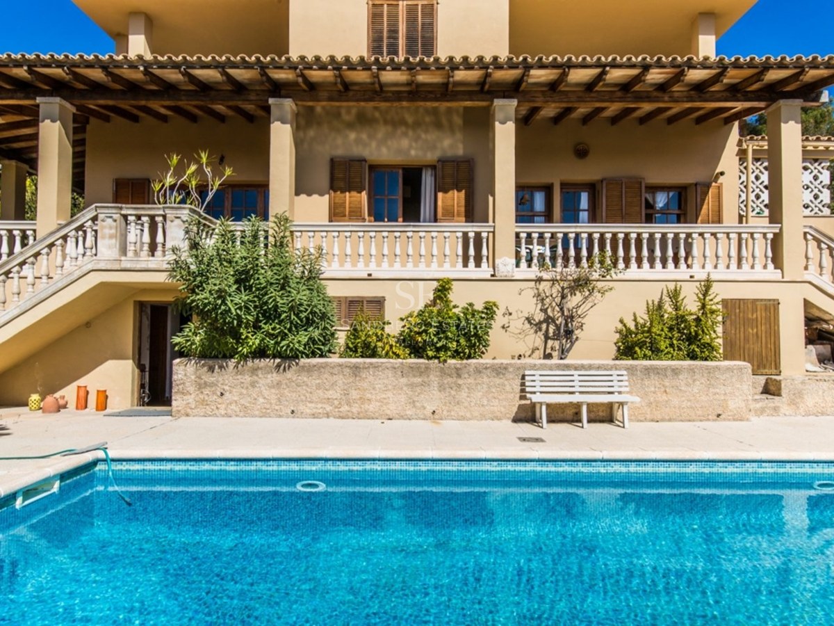 Villa de style méditerranéen avec une grande piscine bleue et une terrasse avec balustrade en pierre.