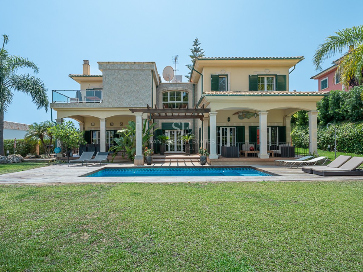 Villa méditerranéenne jaune avec piscine, volets verts, grand jardin et terrasses couvertes par temps clair.