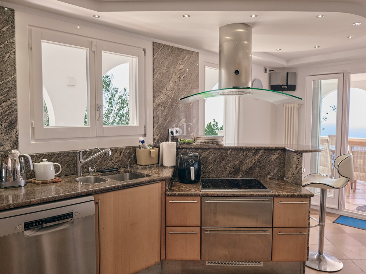 Contemporary kitchen featuring granite countertops, stainless steel appliances, and a view to an outdoor dining terrace.