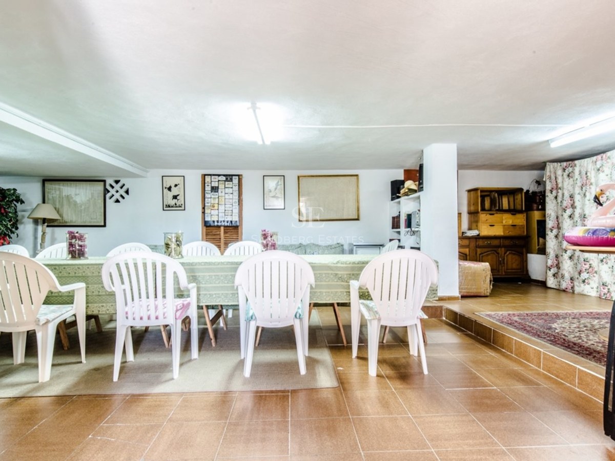 Grande table à manger avec chaises blanches dans une pièce carrelée au décor traditionnel.