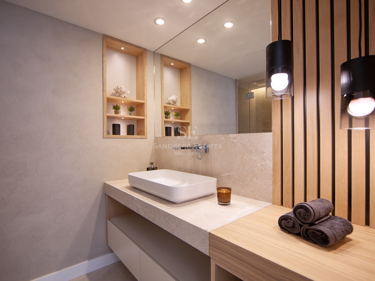 Modern bathroom featuring a white vessel sink, stone countertop, wooden slat wall, and warm pendant lighting.