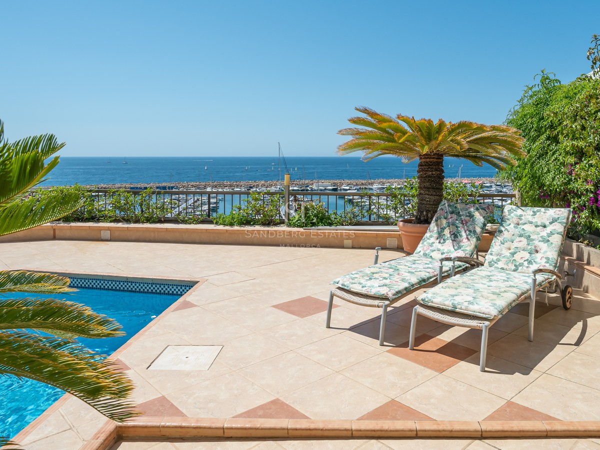 Elevated terrace with a swimming pool, sun loungers, and a panoramic view of a marina and the Mediterranean sea.