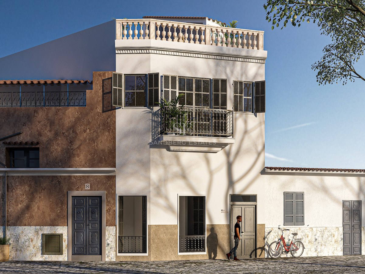 Three-story white and ochre building with traditional shutters, wrought iron balconies, and a stone balustrade on the roof.