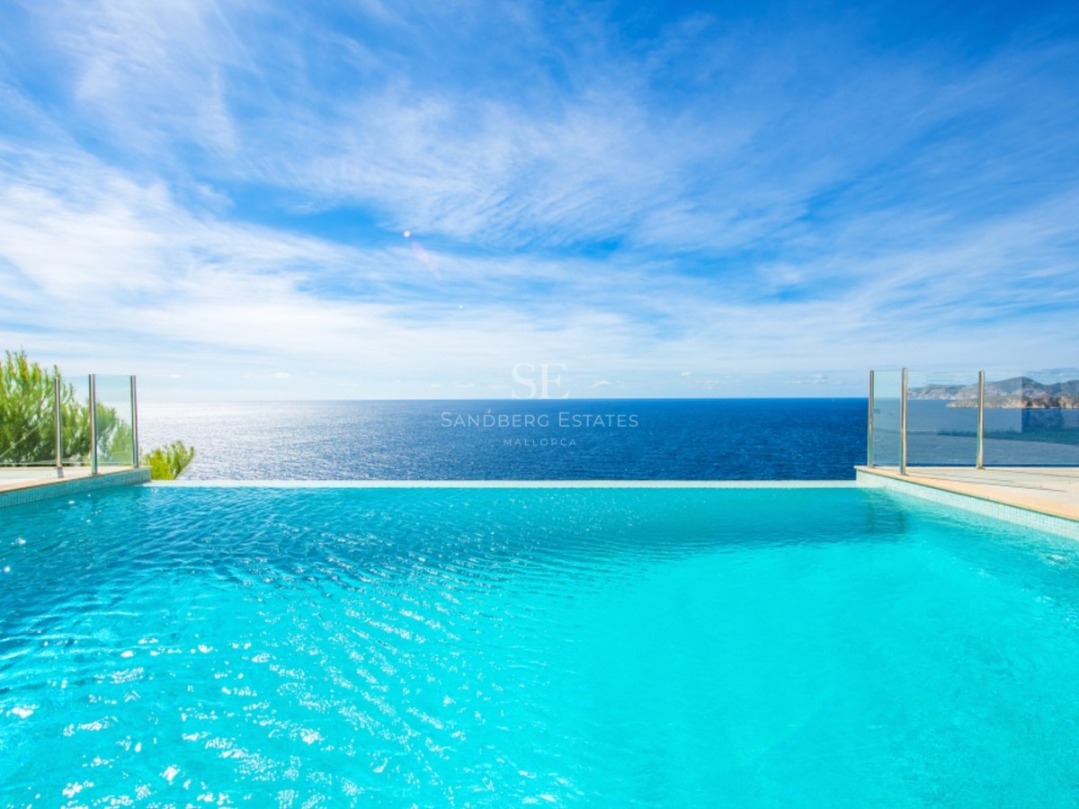 Lyxig infinitypool med utsikt över Medelhavet, glasräcken och klarblå himmel.