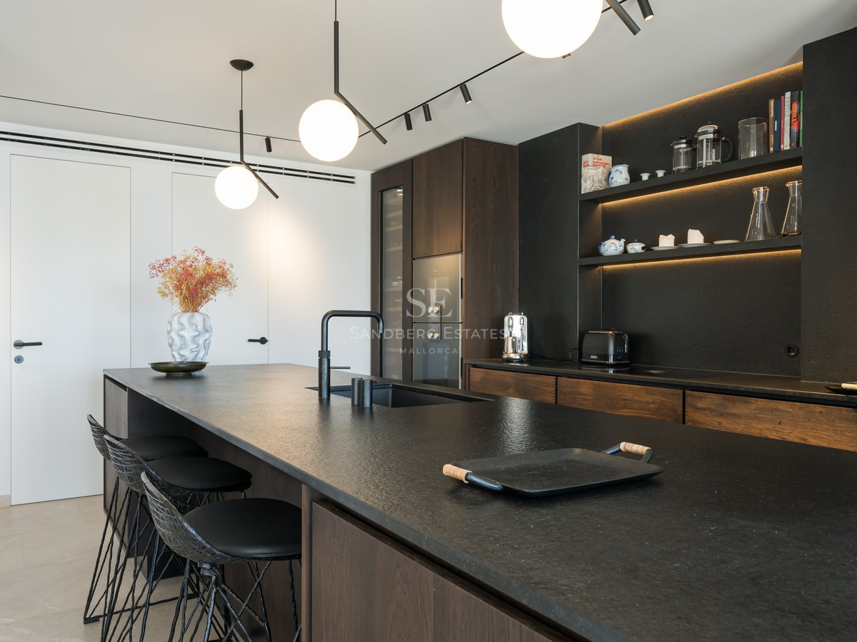Cuisine contemporaine dotée d'un îlot en pierre noire, de placards en bois sombre et de suspensions sphériques.