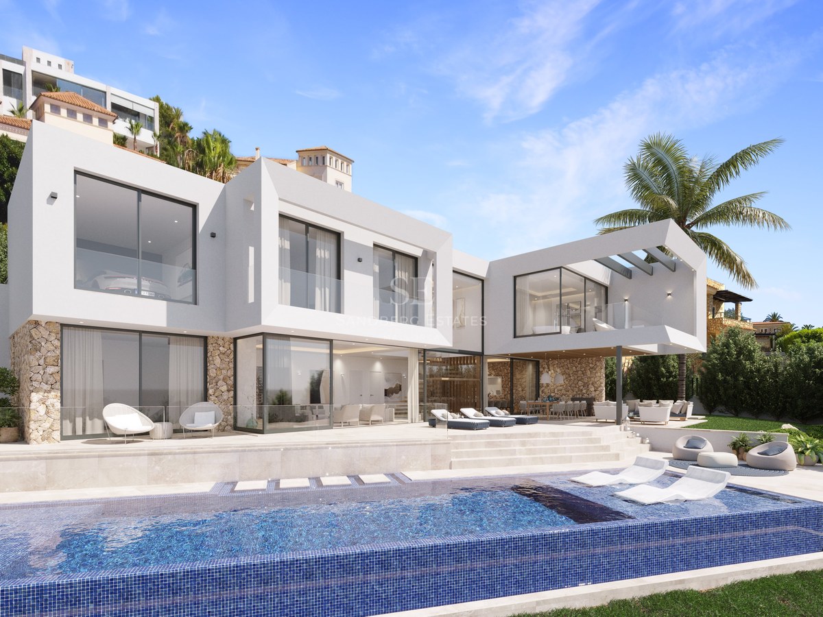 Villa moderne blanche avec piscine à débordement, chaises longues, garde-corps en verre et murs en pierre naturelle.