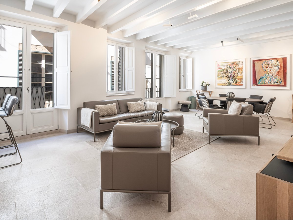 Spacious living room with taupe leather sofas, white beamed ceiling, and large windows with shutters.