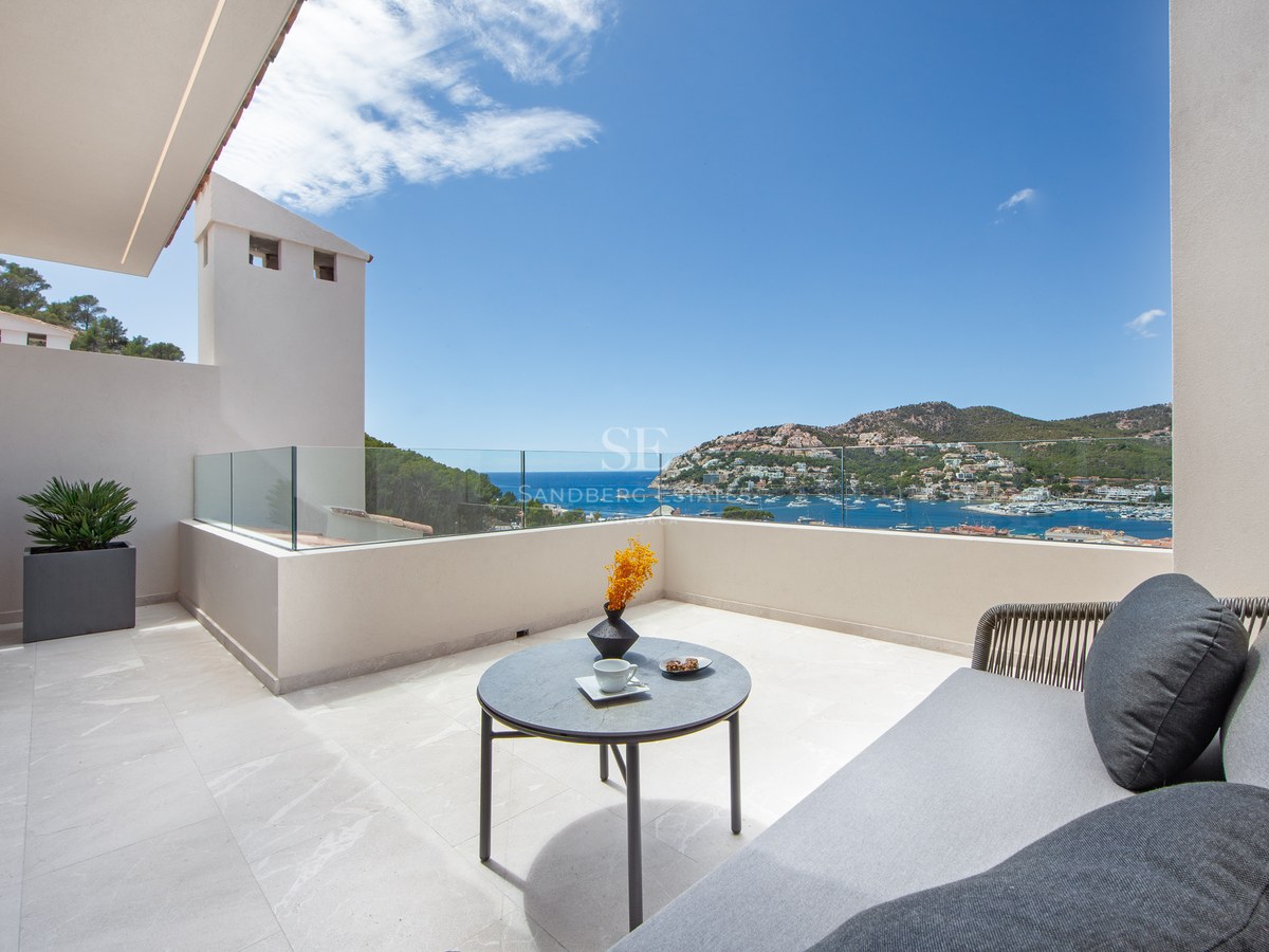 Luxury terrace with glass railings, outdoor sofa, and a breathtaking view of a Mediterranean harbor.