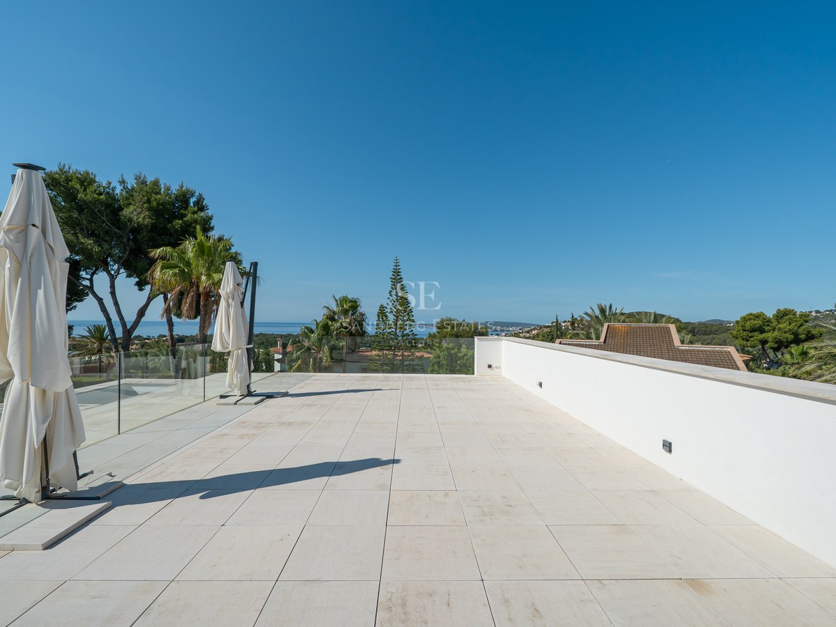 Grande terrasse en pierre blanche avec garde-corps en verre surplombant la mer Méditerranée.