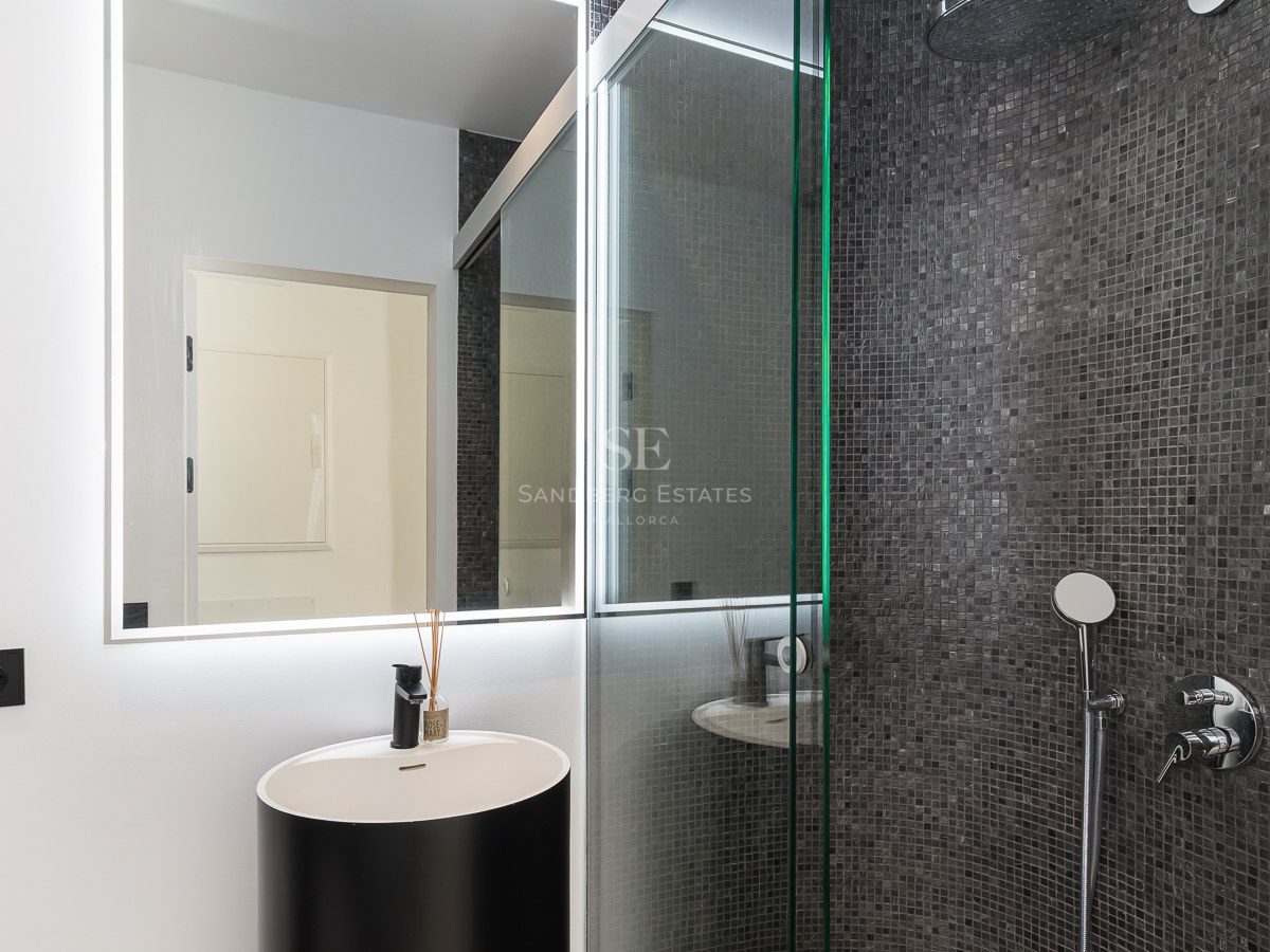 Zeitgenössisches Badezimmer mit schwarzem Design-Waschtisch, LED-Spiegel und begehbarer Mosaik-Dusche in Anthrazit.