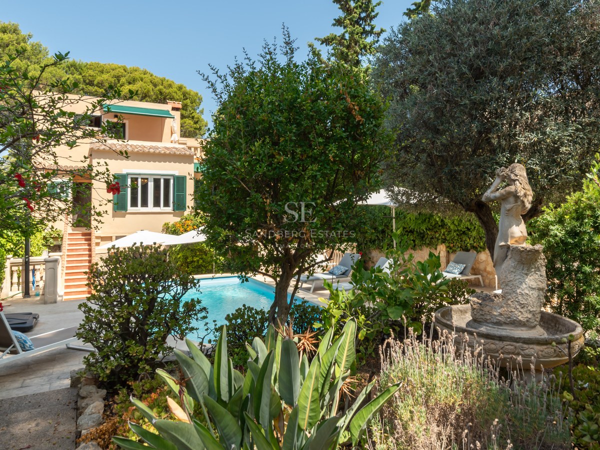 Piscine privée entourée de jardins méditerranéens, une statue classique et une villa aux tons terre cuite.