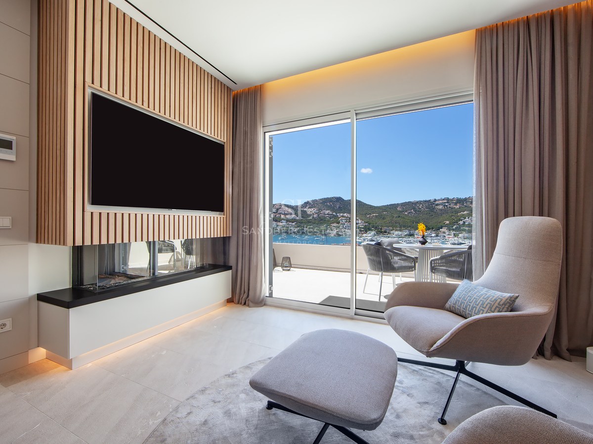 Contemporary lounge featuring an armchair, fireplace, wood-slat TV wall, and panoramic harbor views through sliding doors.