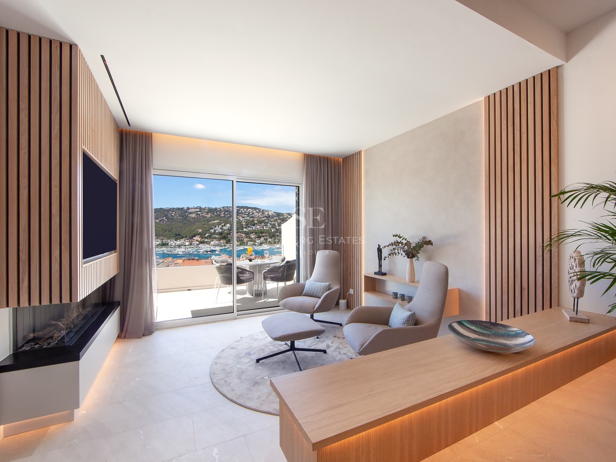 Modern lounge with wood slats, designer chairs, and a sliding glass door revealing a stunning Mediterranean harbor view.