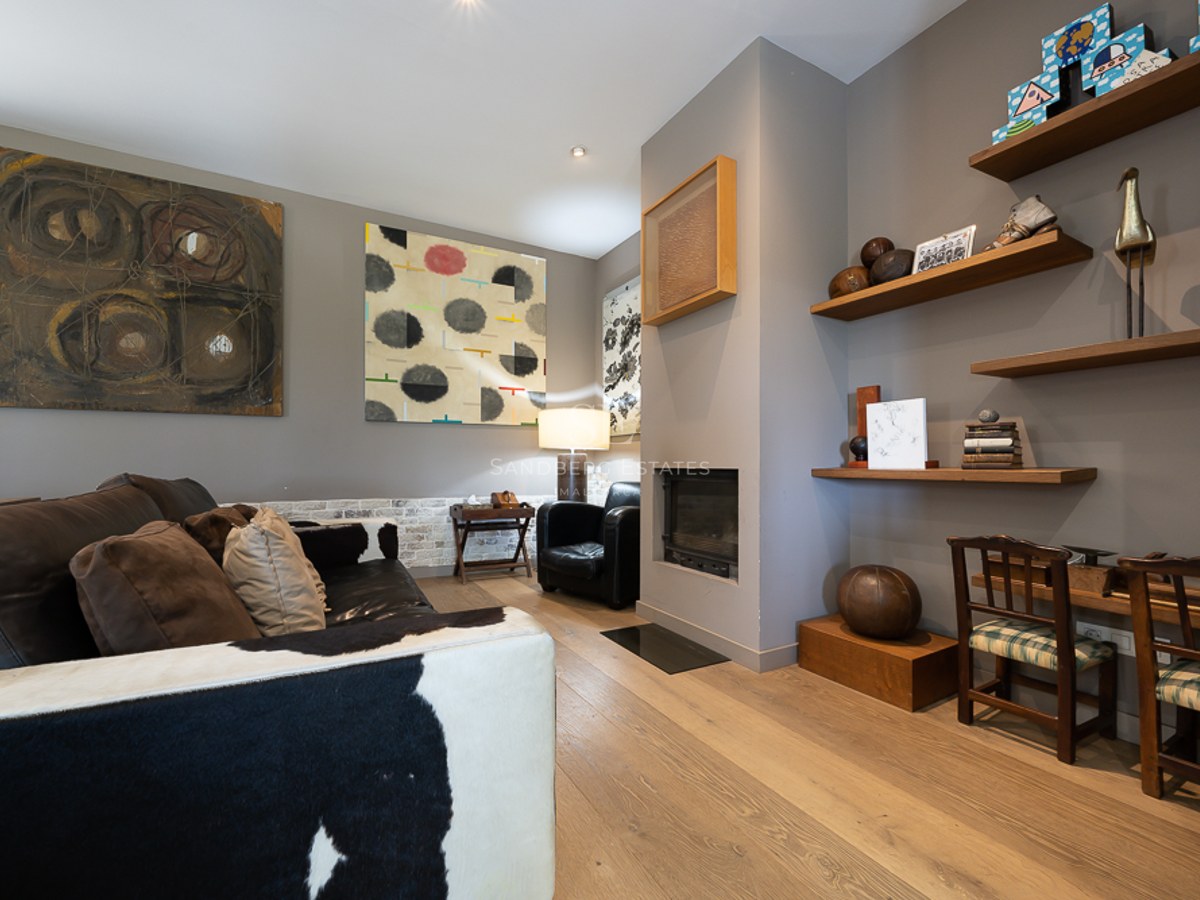 Salon moderne avec canapé en peau de vache, cheminée minimaliste, parquet en chêne et art éclectique.