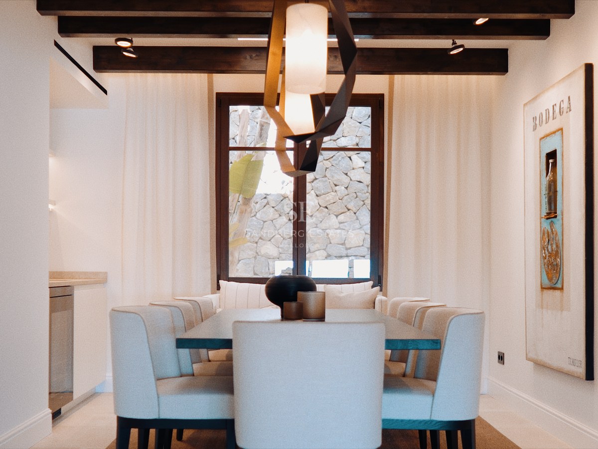 Contemporary dining room with neutral upholstered chairs, a sculptural pendant lamp, and dark wooden ceiling beams.