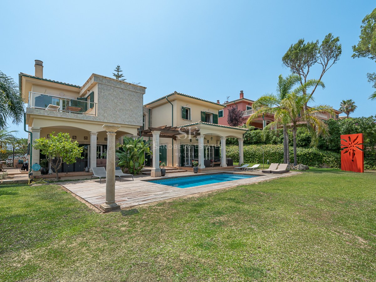 Extérieur de villa de luxe avec piscine, terrasse en bois, grand jardin et architecture méditerranéenne traditionnelle.