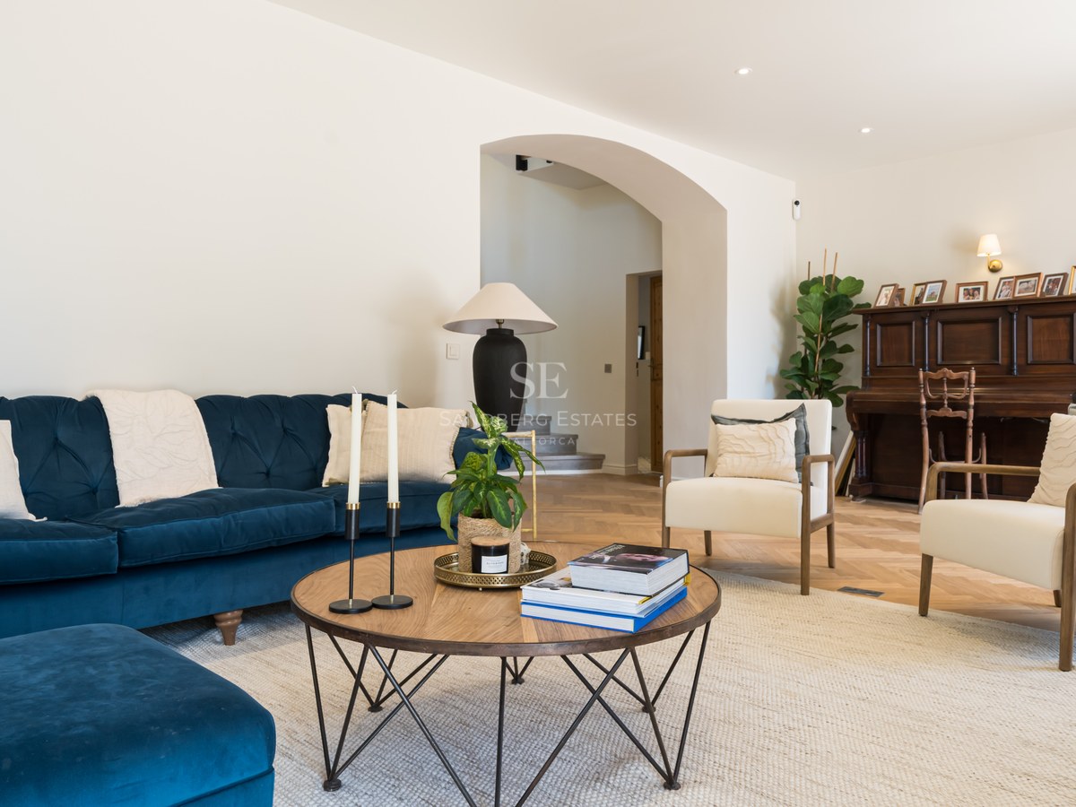 Luxury living room featuring a navy blue velvet sofa, herringbone wood floors, and a classic piano in the background.