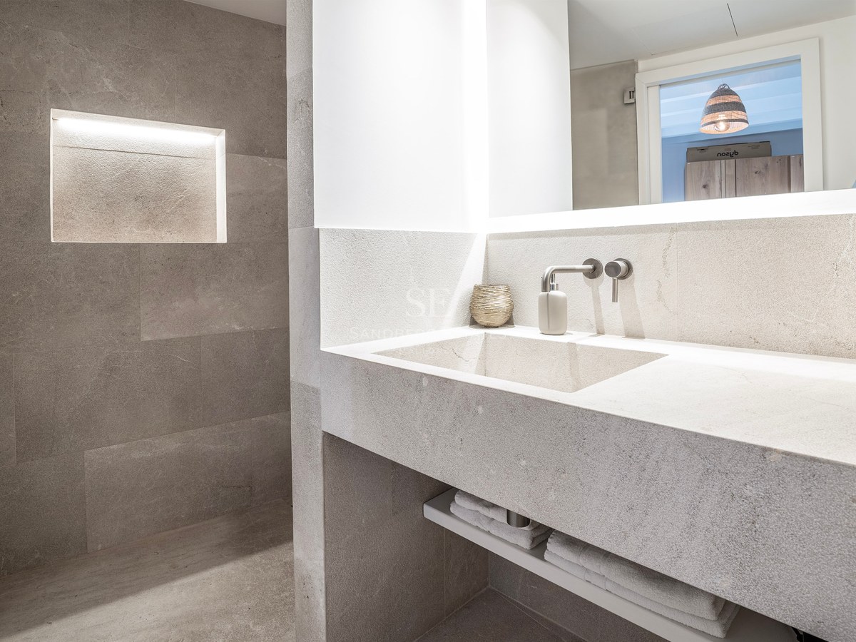 Modern stone bathroom featuring an integrated sink, wall-mounted faucet, and a glowing recessed niche in the stone wall.