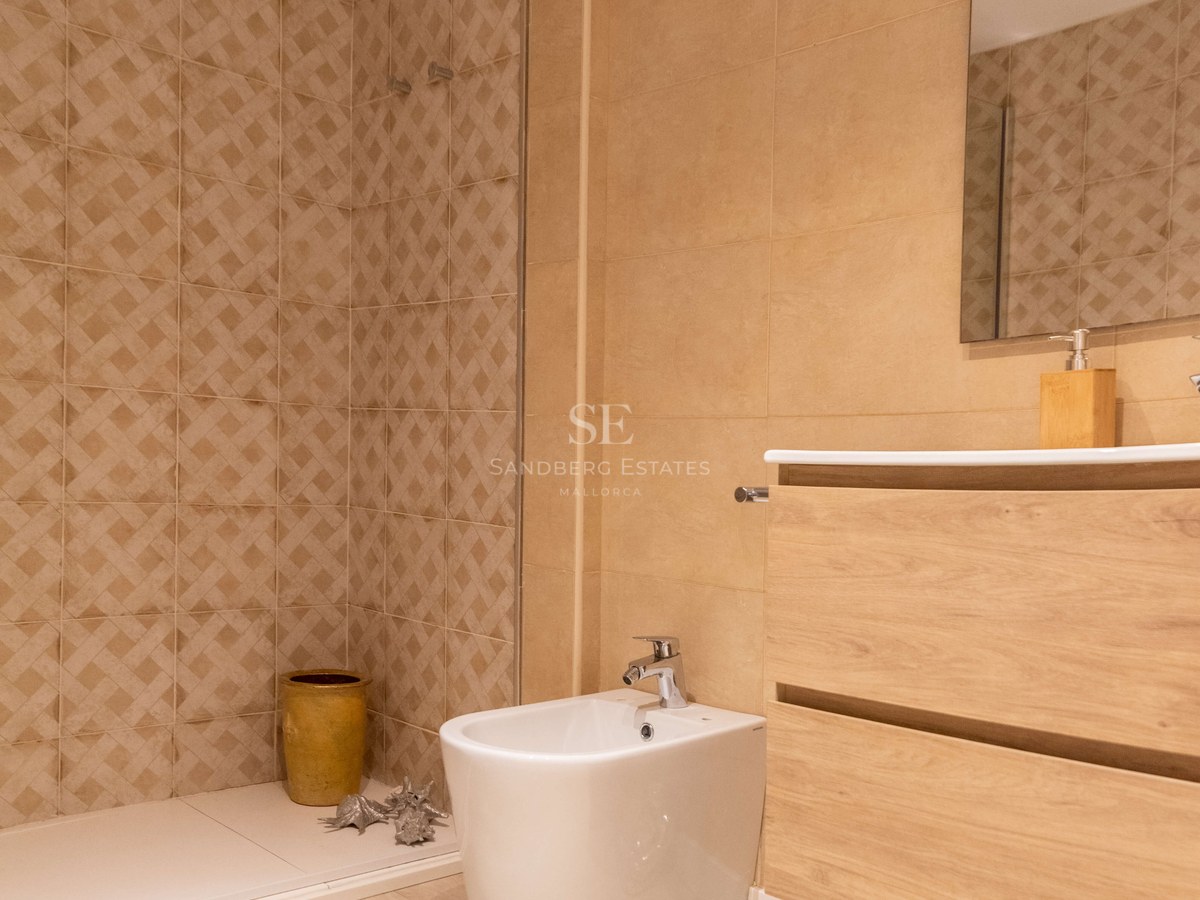 Salle de bain contemporaine avec carrelage tons sable, douche à l'italienne, meuble vasque en bois et bidet blanc.