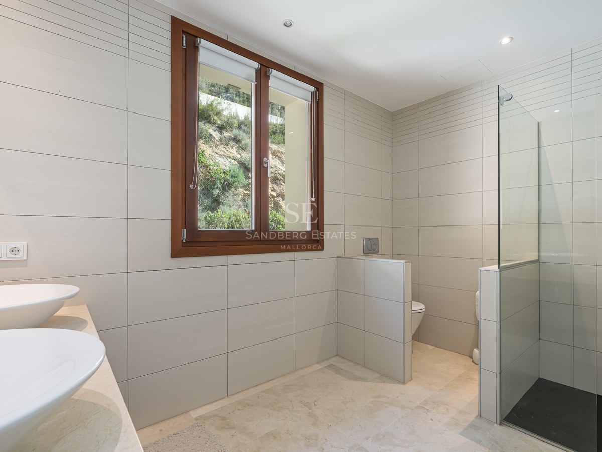 Baño contemporáneo con lavabos de seno, ducha de cristal con suelo de pizarra y ventana con marco de madera.