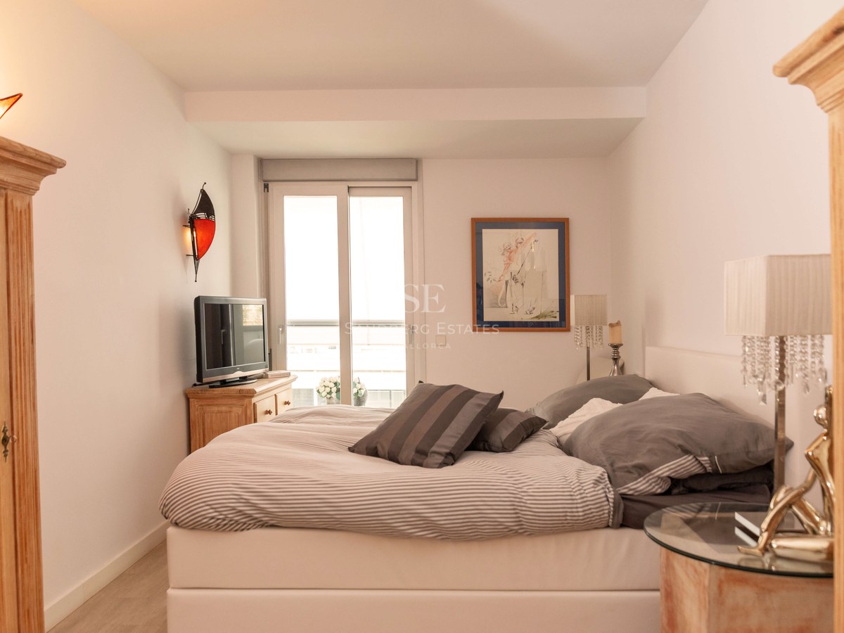 Chambre à coucher avec un grand lit, des meubles en bois, des lampes en cristal et un balcon attenant.