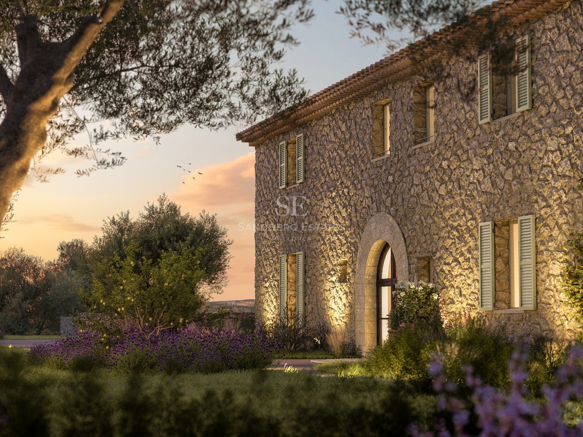 Façade en pierre d'une villa de luxe au coucher du soleil avec entrée voûtée et oliviers.