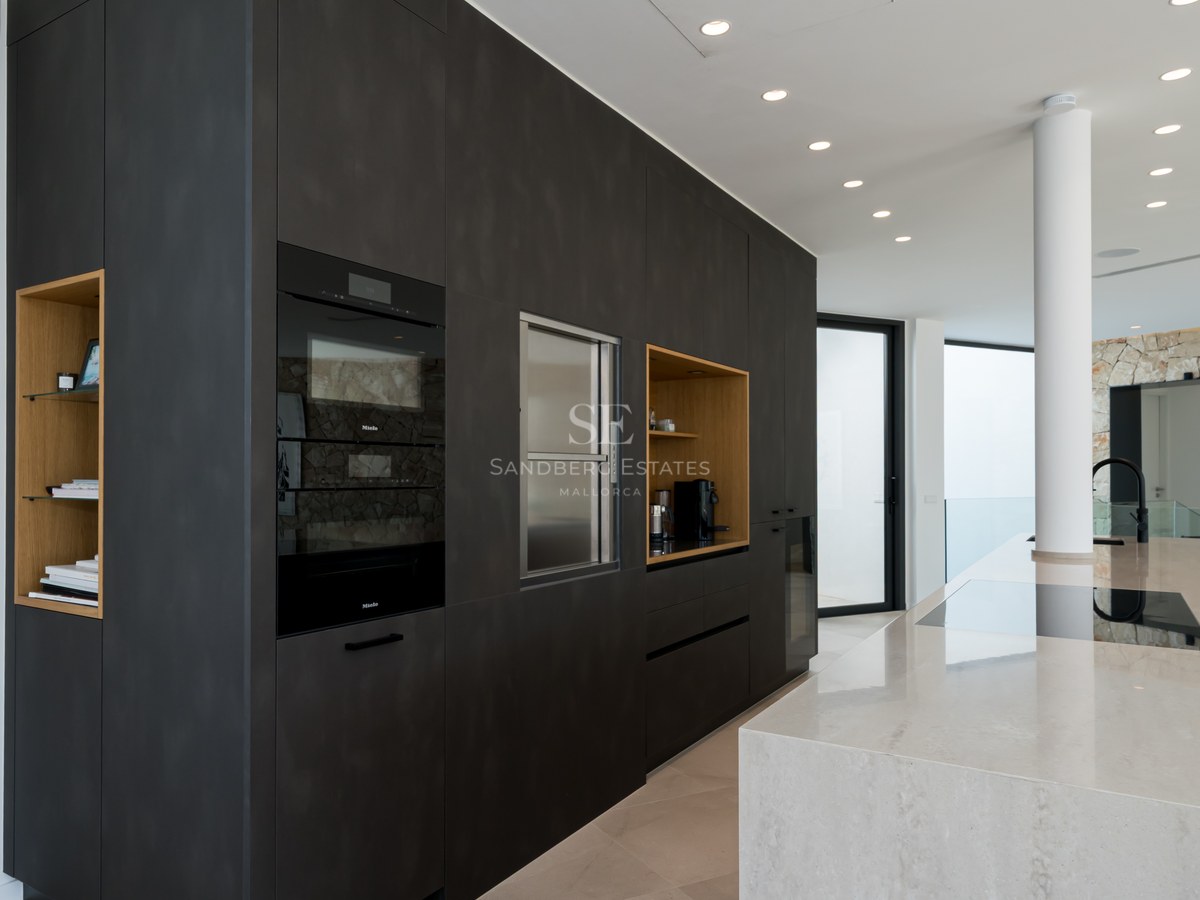 Cuisine moderne avec placards anthracite, îlot en marbre et fours Miele intégrés dans un espace lumineux.