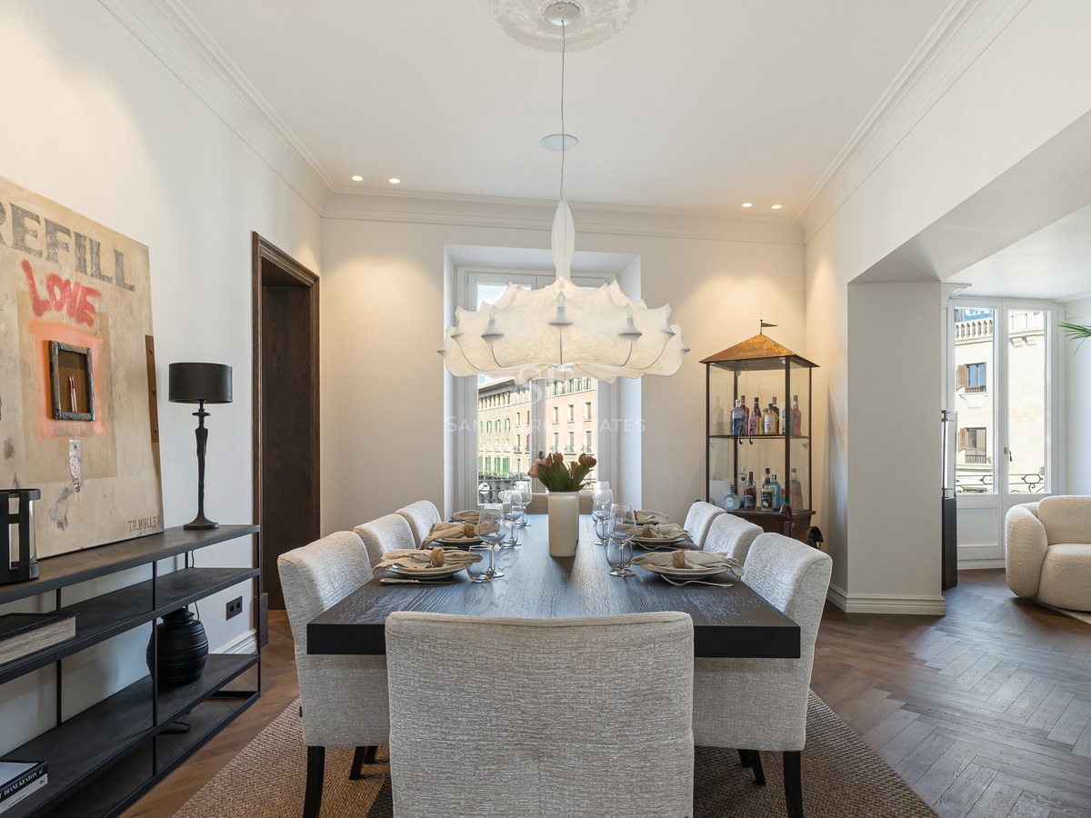 Comedor contemporáneo con mesa de madera oscura, sillas tapizadas, lámpara de diseño y suelos de roble en espiga.