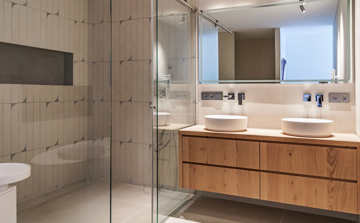 Salle de bains contemporaine avec meuble en bois suspendu, deux vasques blanches et douche à l'italienne.