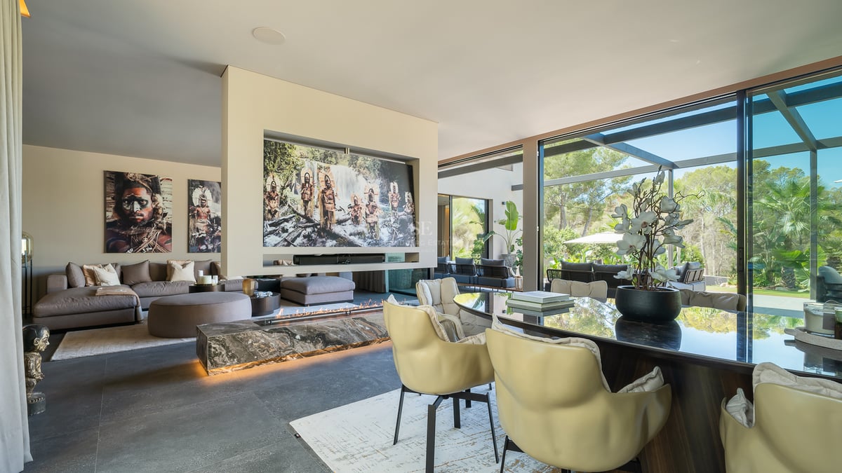 Salon de luxe à aire ouverte avec cheminée en marbre, mobilier moderne et baies vitrées sur le jardin.
